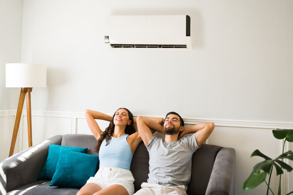Couple lounging with an air conditioner on a hot summer day.