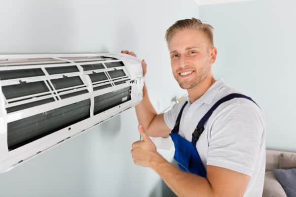 smiling technician gesturing thumbs up with ductless ac